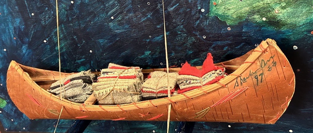 Indigenous Canadian Artist Sheila Orr - Artwork titled Returning Tainted Gifts, 1999 - A mixed media  artwork showing a canoe stacked with blankets attached to painting of the sea.