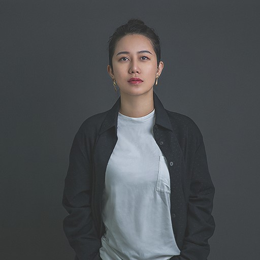 Xiao Han - Portrait of young Asian woman wearing a dark grey jacket and a light grey t-shirt.