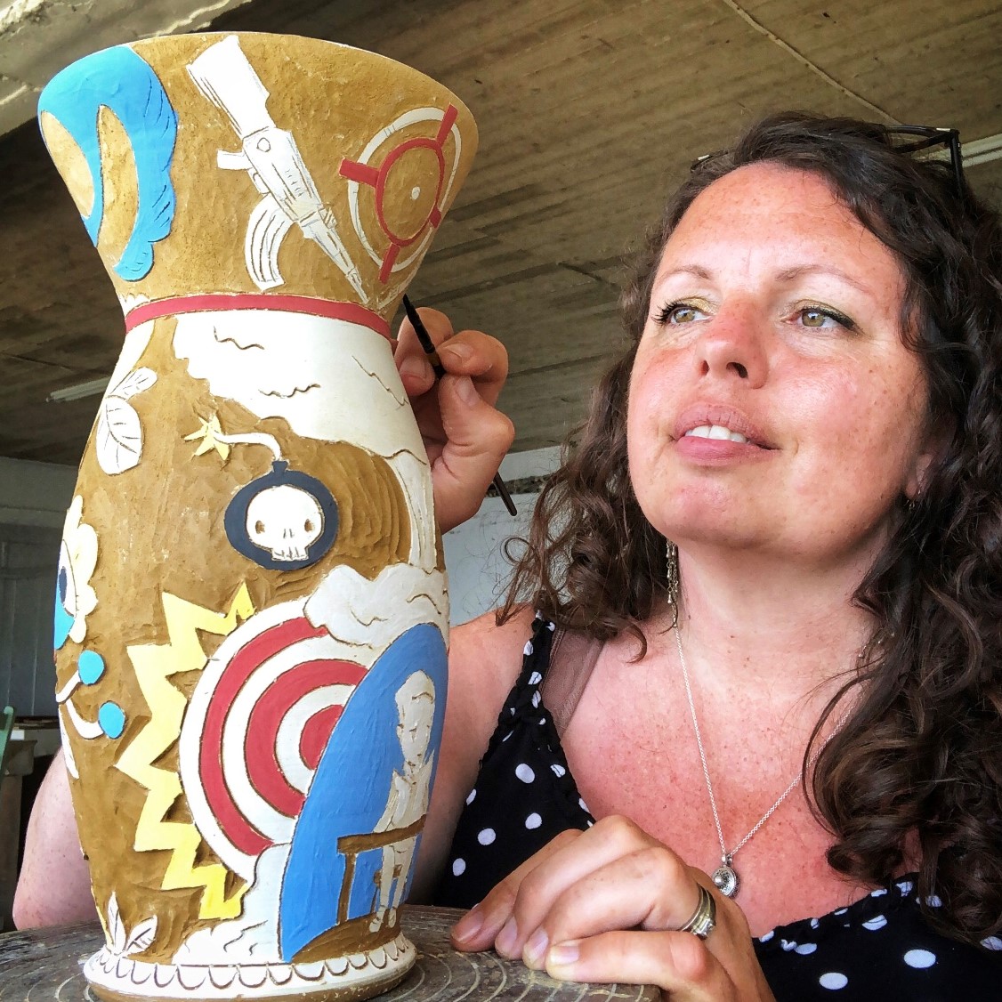 Carole Epp, SK Arts 75th anniversary nominator - Woman with curly hair decorating a ceramic vase. 