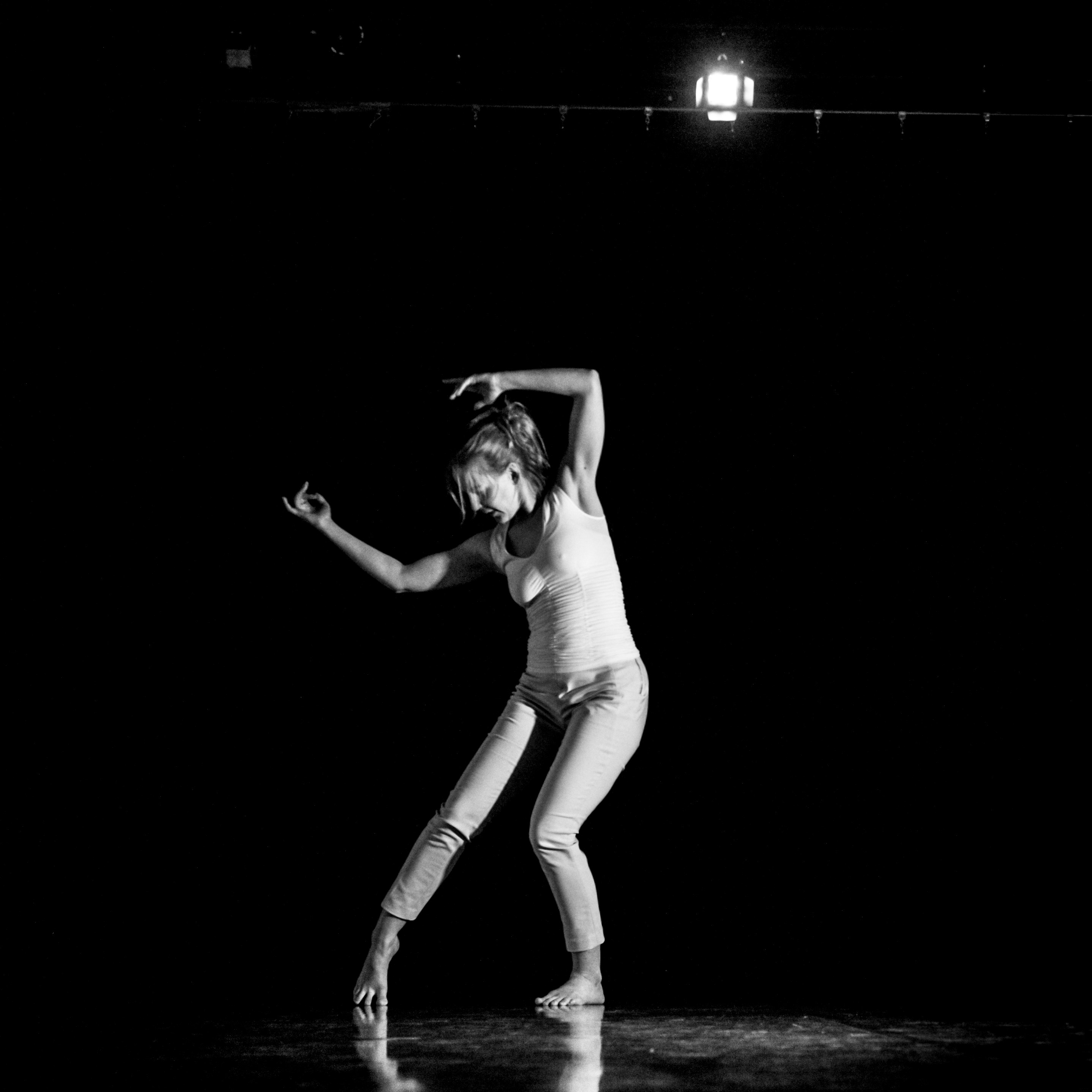 Krista Solheim - Black and white shot of woman dancing with dark background.