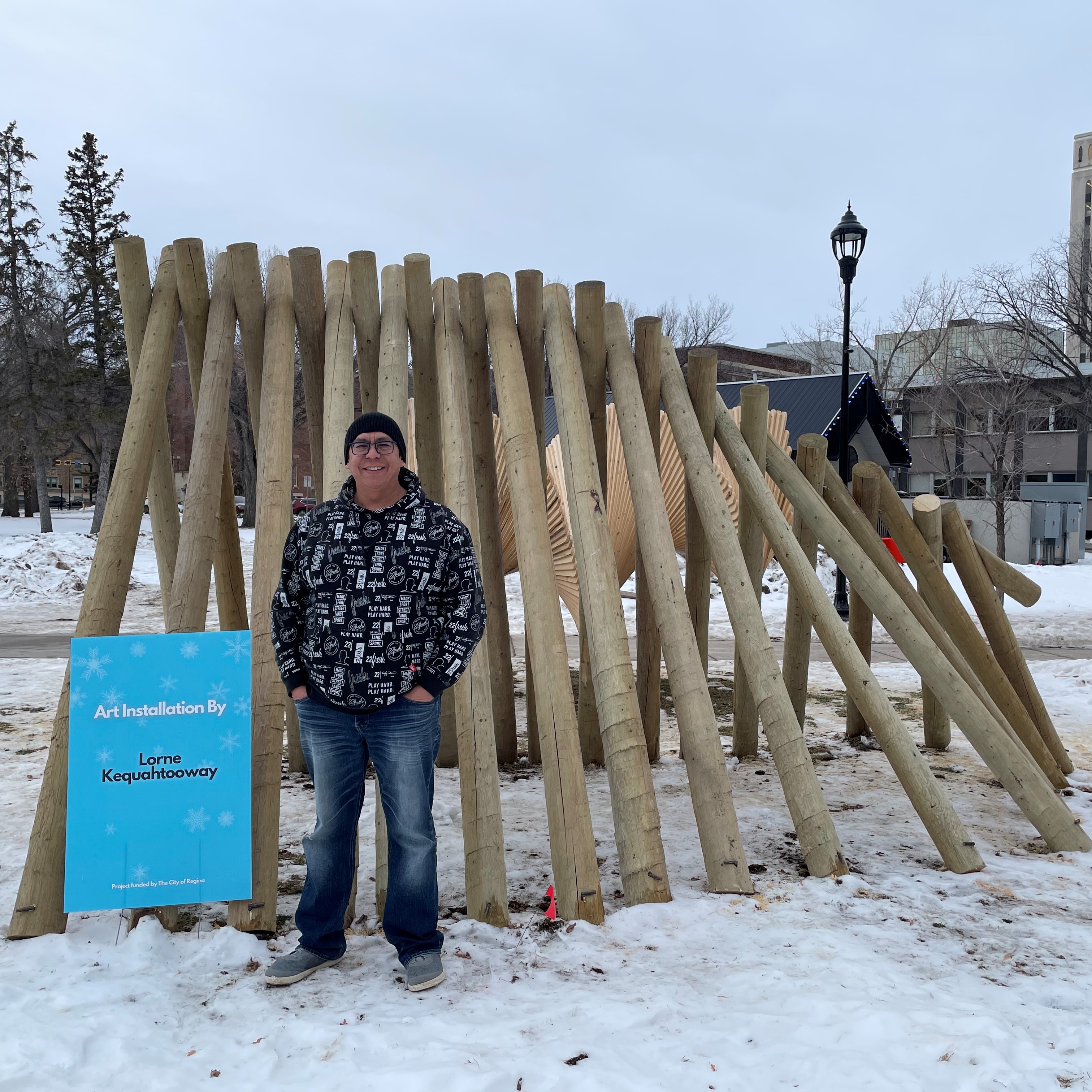 Lorne Kequahtooway - Man standing in front of a sculpture in winter.