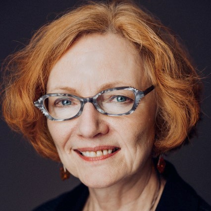 Mari-Lou Rowley - Older woman with short ginger red hair and glasses smiling.