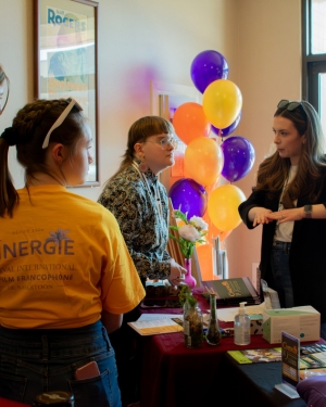 Photo of three people at a desk at CINERGIE festival interacting. 