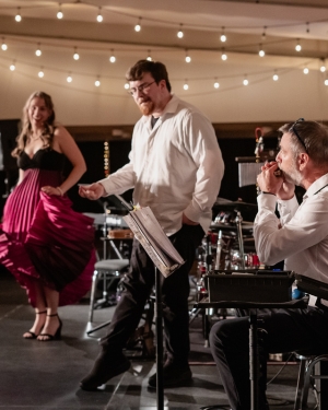 A woman dancing on stage with one man dancing and one was playing the Harmonica - Listen To Dis Daniel Paquet