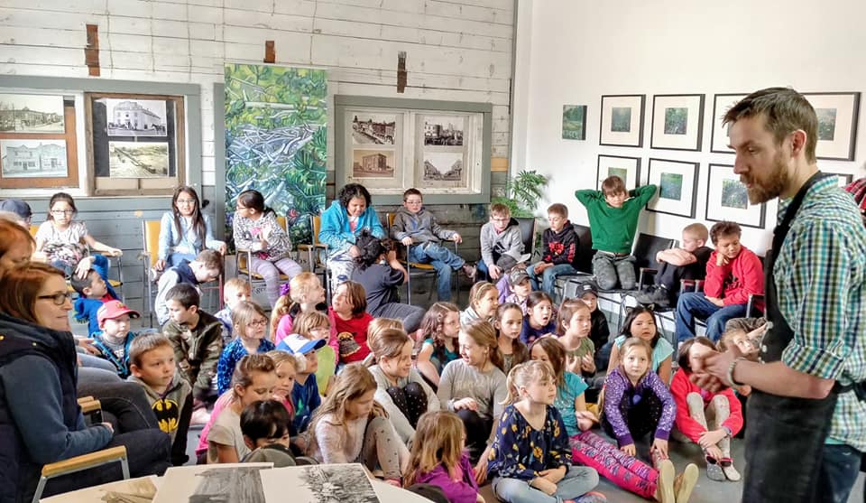 SKArts - Artist Geoff Phillips speaks to Sidney Street School students about the art associated with the printing of posters at the turn of the last century encouraging settlers to homestead in the Canadian west.