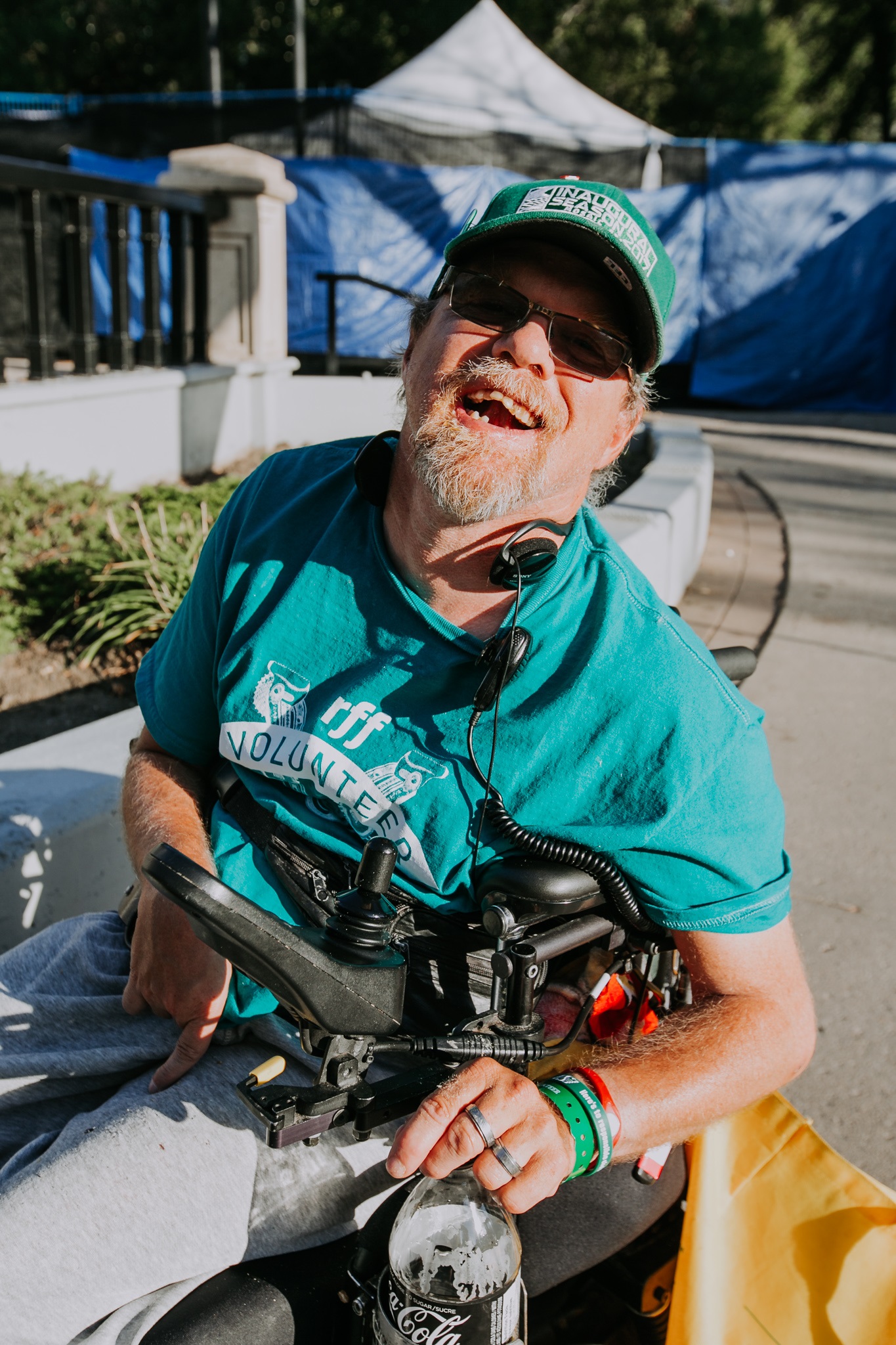 A happy volunteer sitting in a wheelchair at the Regina Folk Festival site.