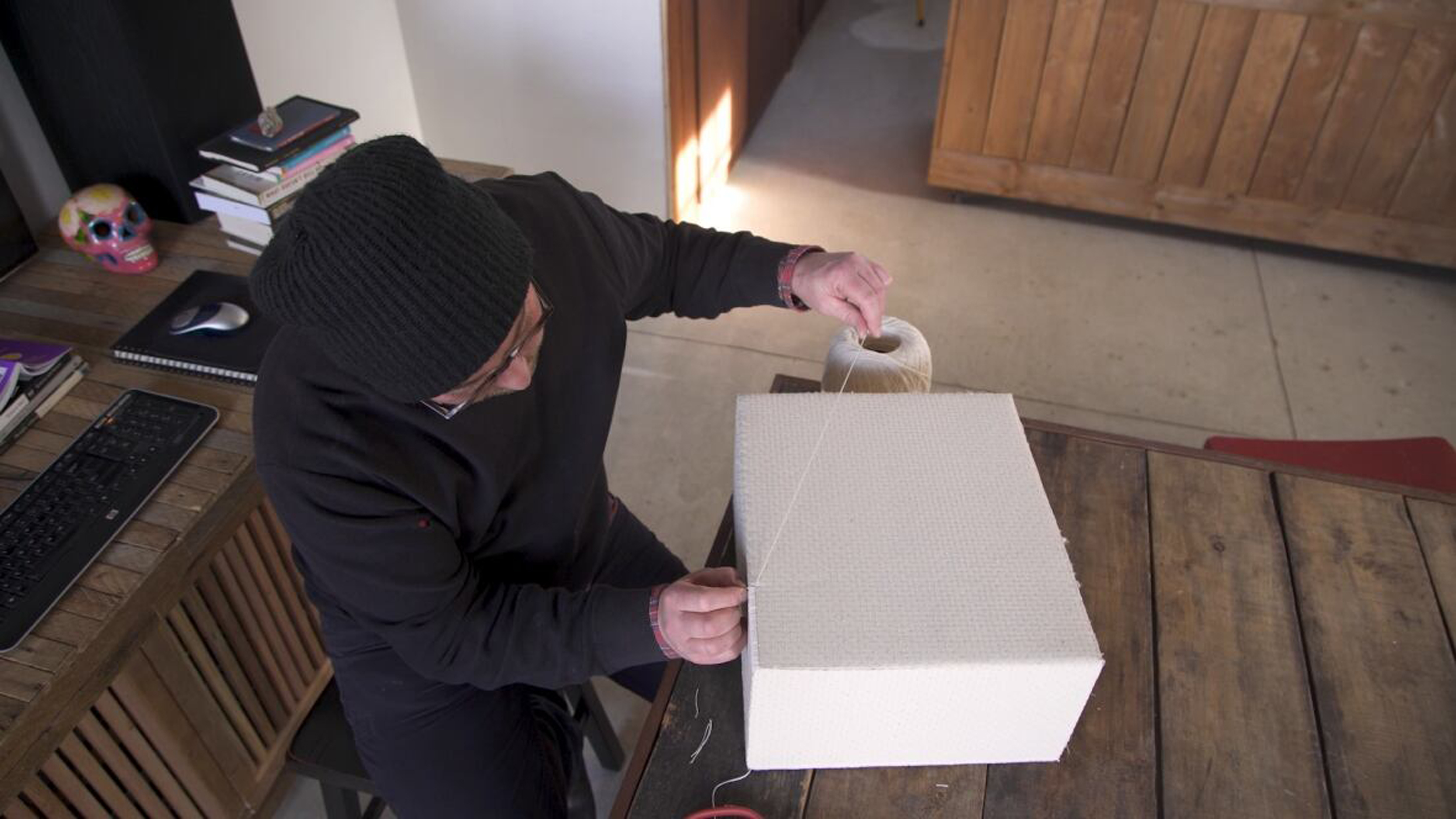 Christopher Campbell Gardiner ties some string around a box in his artist studio.
