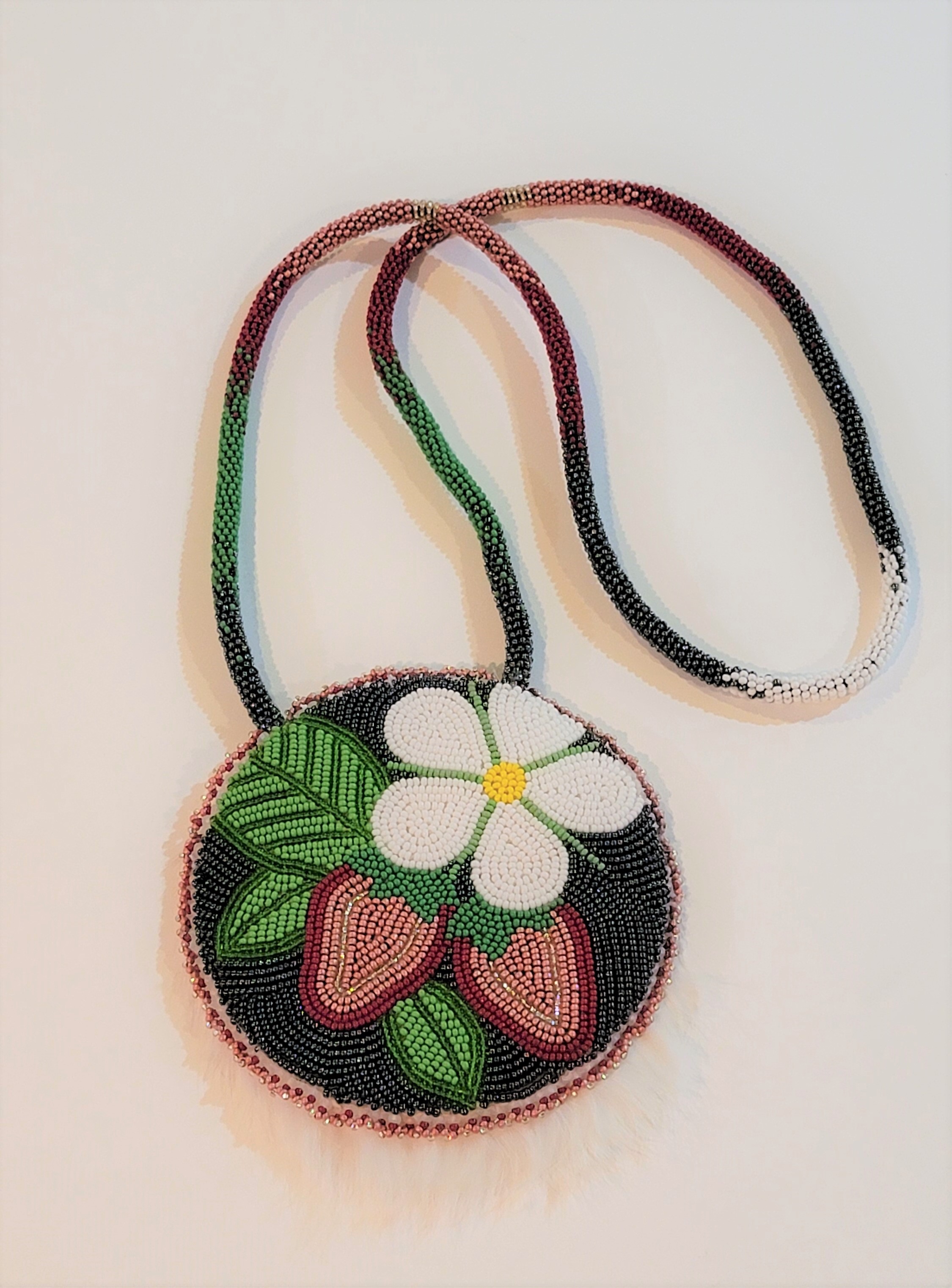 A beaded medallion with straberries and a flower on it