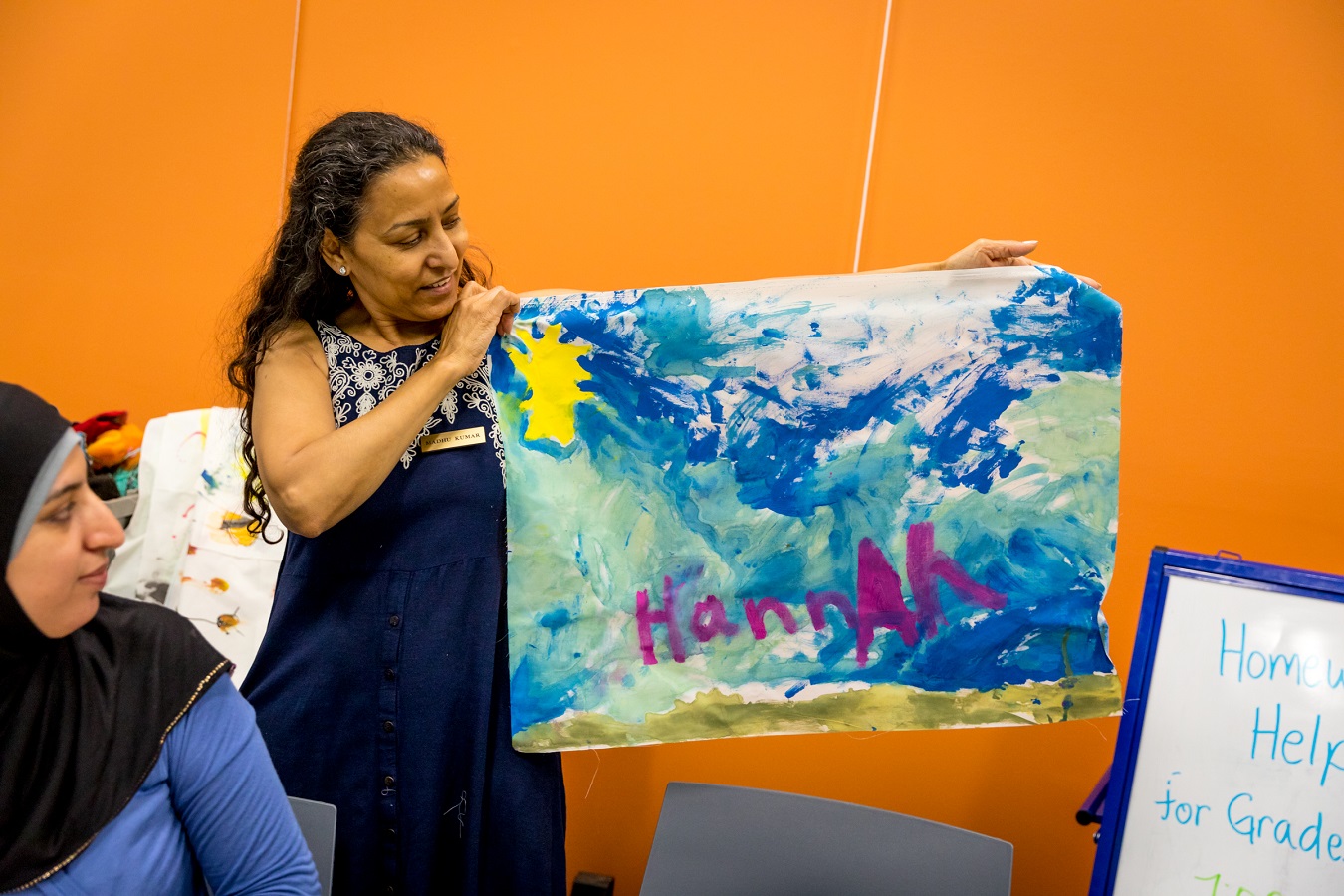 Madhu Kumar holds up a colourful painting by one of the participants in her art sessions at Dunlop Art Gallery.