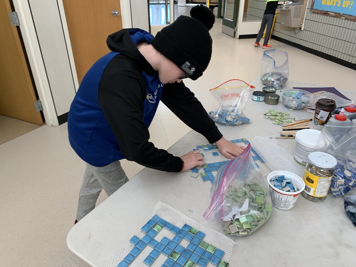 A student uses tiles to create a mosaic.